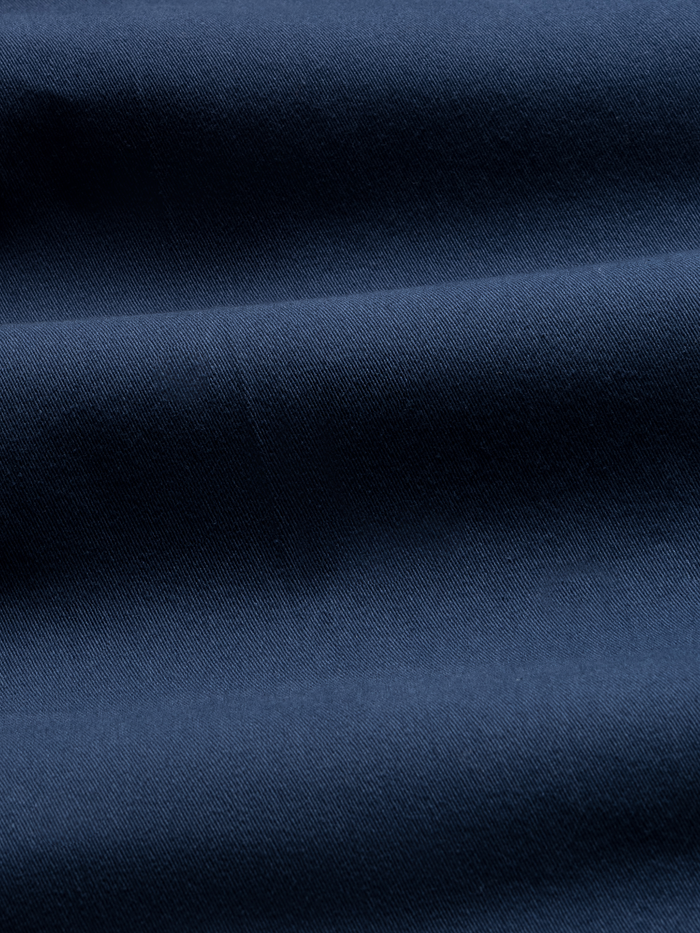 Close-up of navy chino fabric with folds, showing twill texture