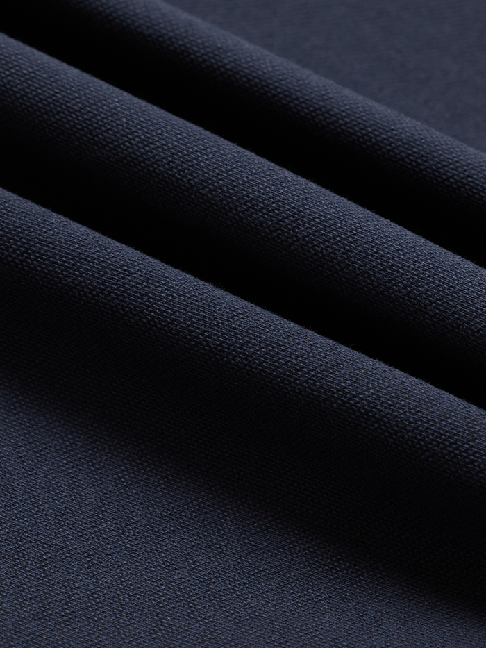 Close-up of navy cotton pique fabric with folds, showing textured weave