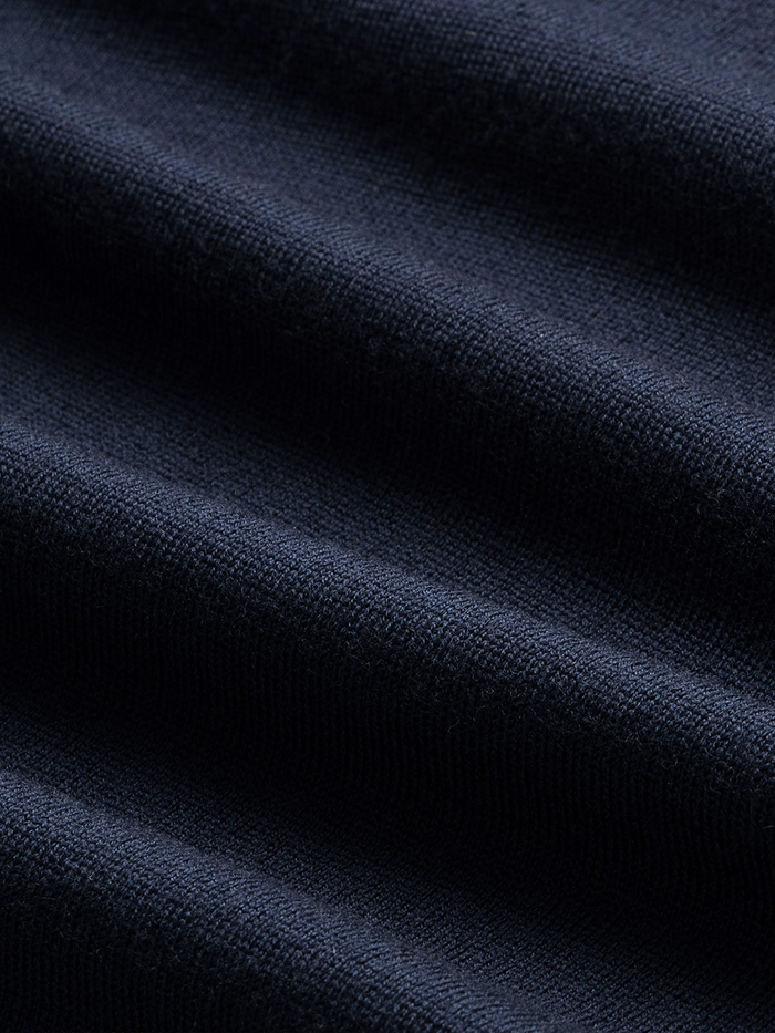 Close-up of navy sweater knit fabric with folds, showing textured weave