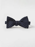 Navy bow tie with white polka dots, tied, on a light grey background
