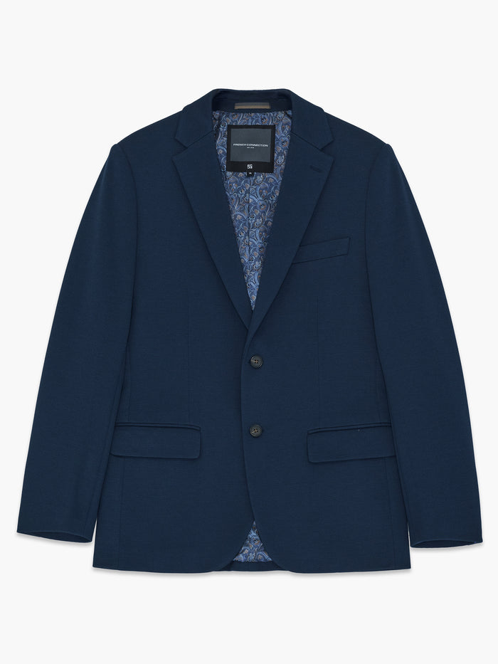 A man wearing a navy Piqué Suit Jacket  with long sleeves, a chest welt pocket and 2 front pockets.