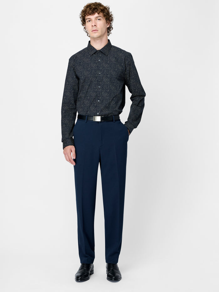 A man wearing navy Piqué tailored trousers with 4 pockets, a zip fly fastening and a front pressed crease.