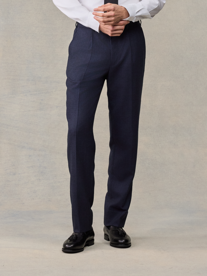 Close-up of man in navy plaid wool suit pants with hands clasped, front view