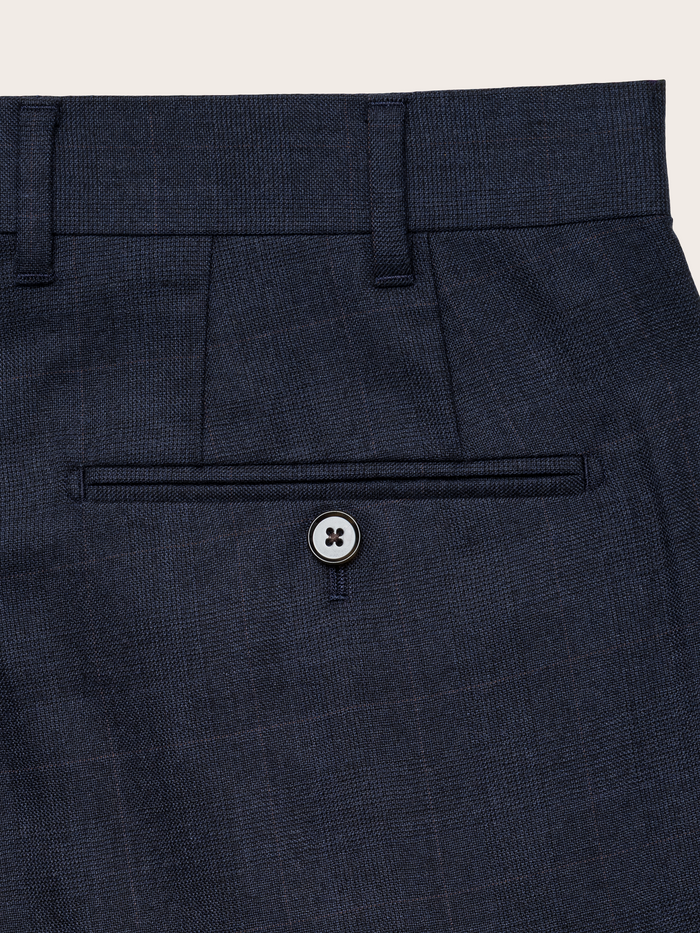 Close-up of navy plaid wool suit pants back welt pocket with button