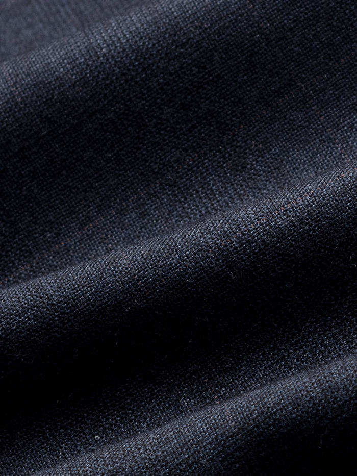 Close-up of navy plaid wool suit fabric with folds, showing woven texture