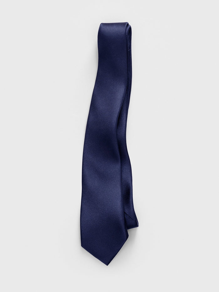 Navy satin necktie laid flat on light grey background