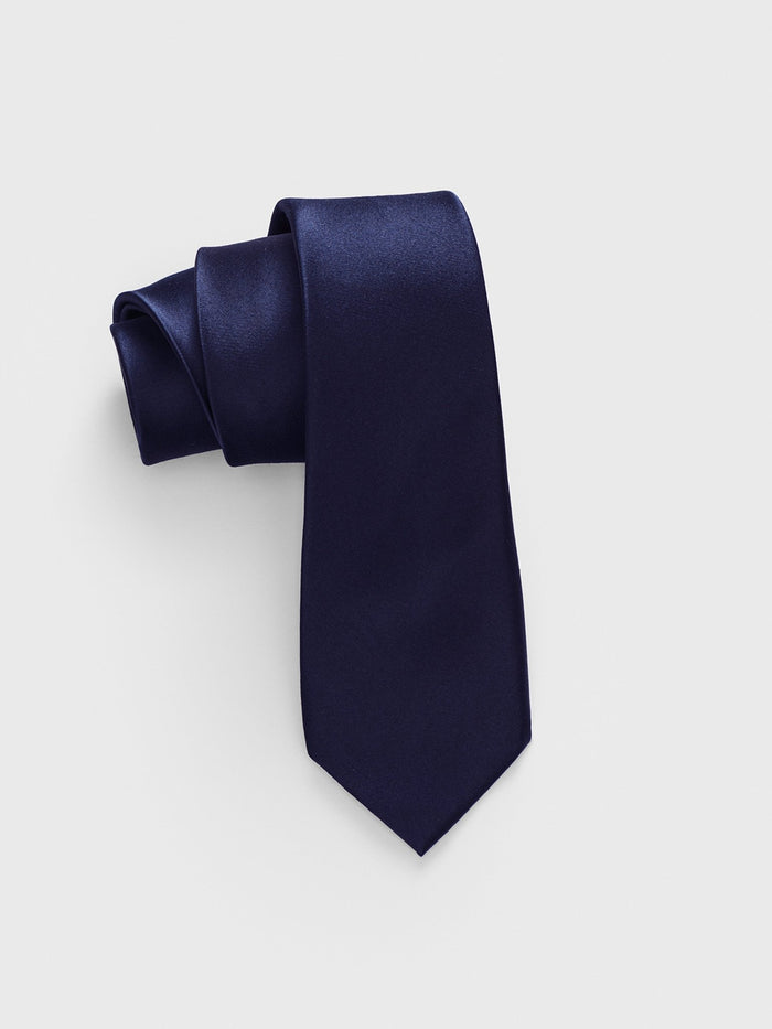 Navy satin necktie rolled into a coil on light grey background