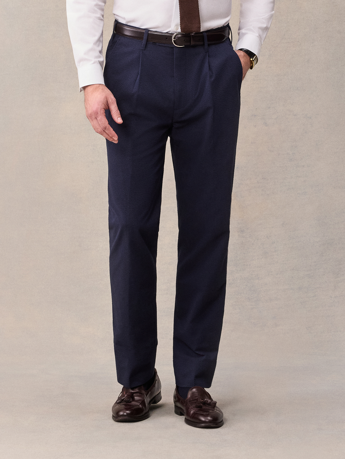 Close-up of man in navy seersucker suit pants with brown belt, hand in pocket, front view