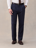 Close-up of man in navy seersucker suit pants with brown belt, hand in pocket, front view