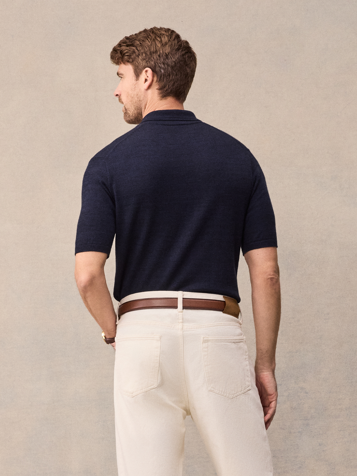 Back view of man in navy short-sleeve sweater polo and cream pants