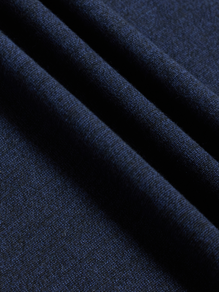 Close-up of navy sweater knit fabric with folds, showing fine-gauge texture