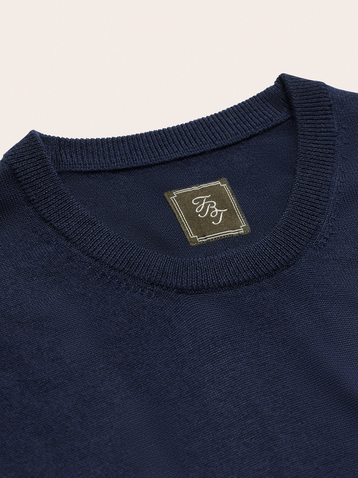 Close-up of navy sweater knit tee crew neckline and brand label