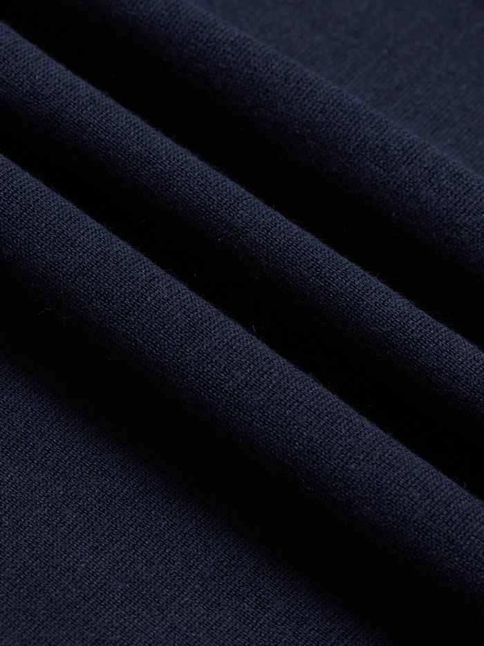 Close-up of navy sweater knit fabric with folds, showing ribbed texture
