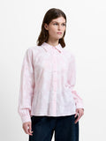 Woman wearing a light pink and white floral jacquard shirt, with dropped long balloon sleeves and a shirt collar