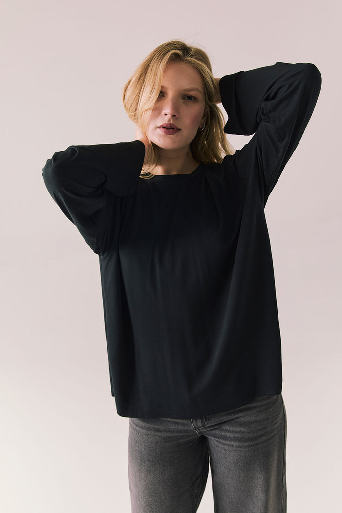 Oversized black long sleeve top with dropped shoulders and relaxed silhouette.