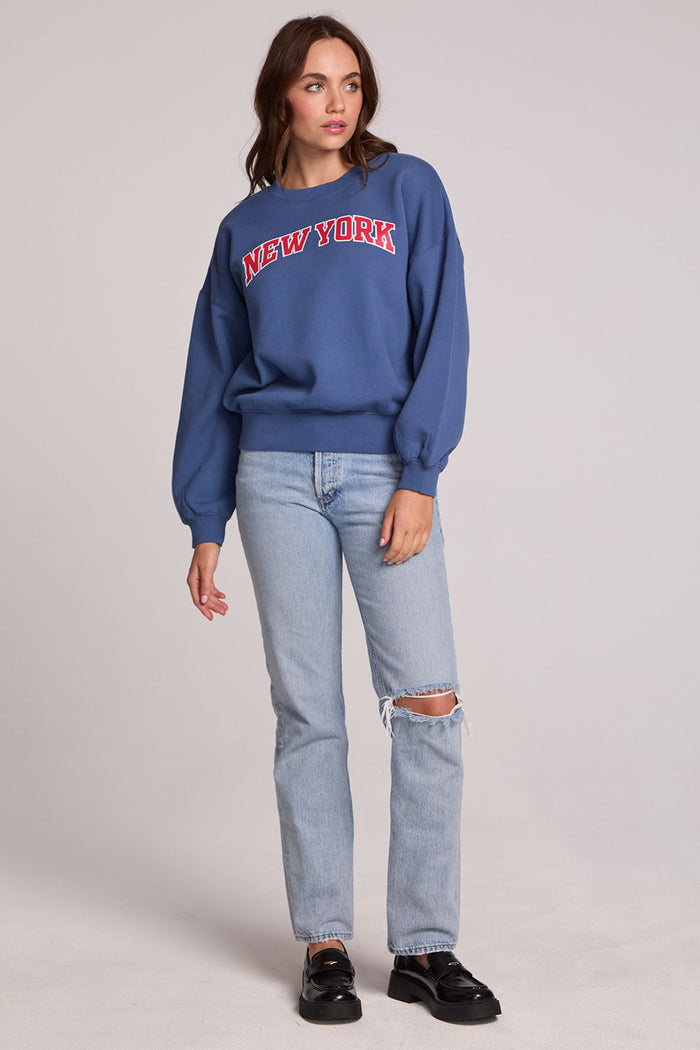 A full body front view of a woman wearing the Chaser New York Long Sleeve on a neutral background