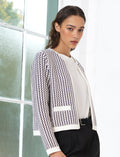 Woman wearing a pink, white and blue abstract patterned cardigan, with long sleeves and a crew neckline