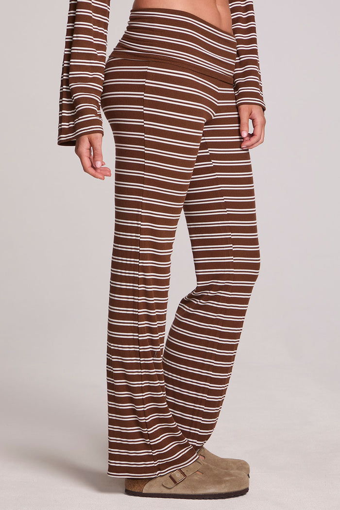 Side angle view of a woman wearing the Chaser Noorh Nutty Brown Stripe Pants on a neutral background with arms lowered