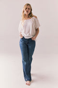 Full front view of Northridge Tee in white with cold shoulder cutout and flowy fit and blue jeans against a plain background