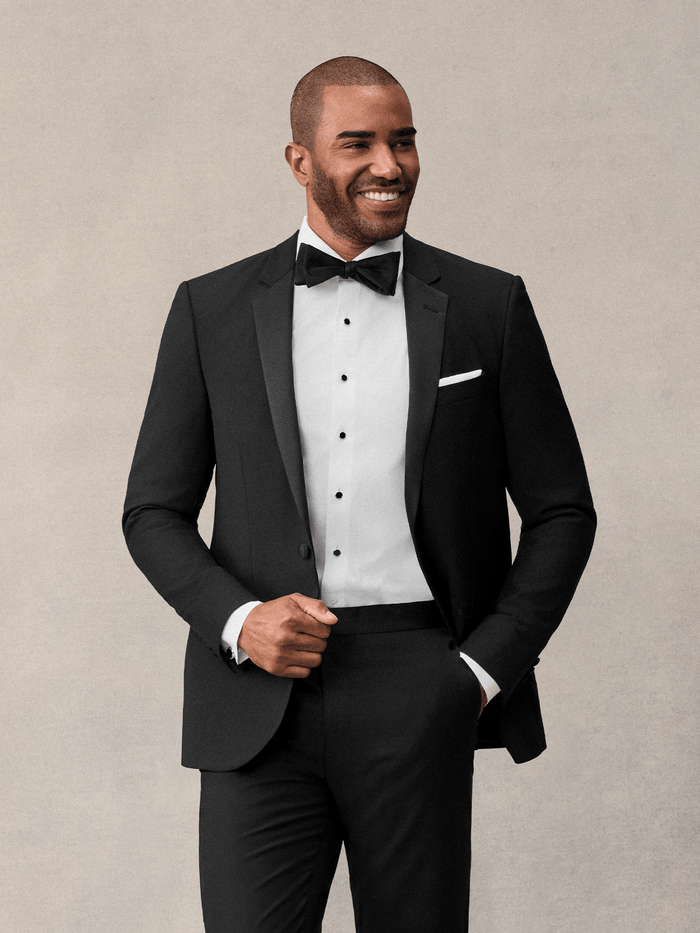 Close-up of man in black notch lapel tuxedo jacket with bow tie and white pocket square