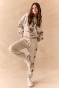 Full front view of NYC Stars Joggers in Heather Grey with smoky plum star print down each leg and matching top, styled for a casual lounge look, against a beige background