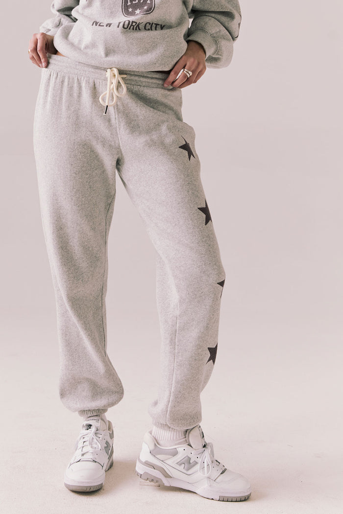 Front view of NYC Stars Joggers in Heather Grey with smoky plum star print down each leg, styled for a casual lounge look, against a plain background