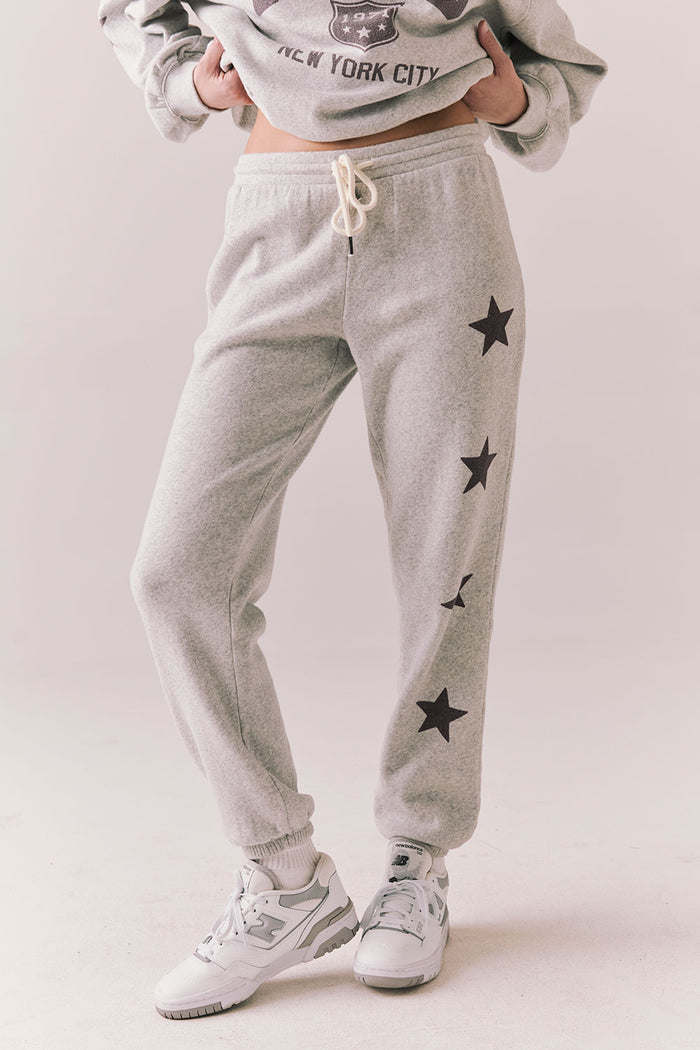 Side view of NYC Stars Joggers in Heather Grey with smoky plum star print  down each leg, styled for a casual lounge look, against a plain background