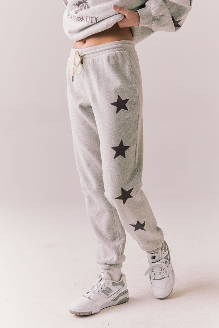 Side view of NYC Stars Joggers in Heather Grey with smoky plum star print  down each leg, styled for a casual lounge look, against a plain background