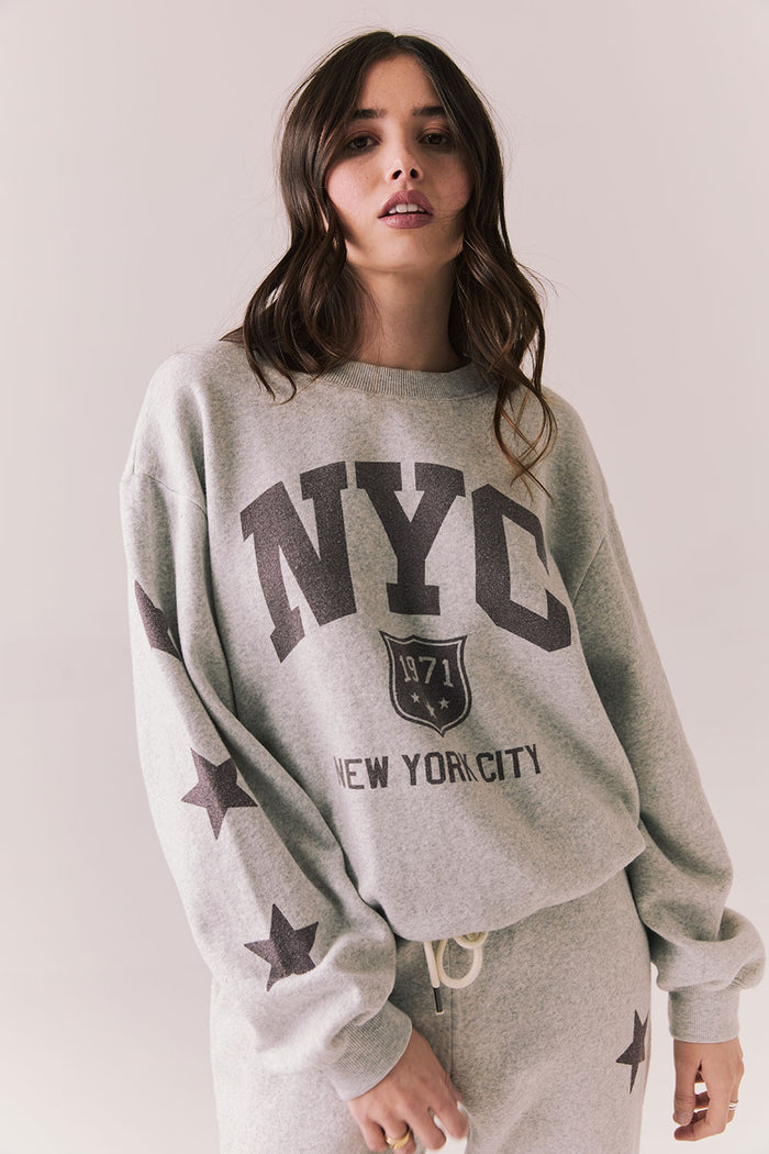 Front view of NYC Stars Pullover in Heather Grey with bold chest lettering and smoky plumb star sleeves against a plain background