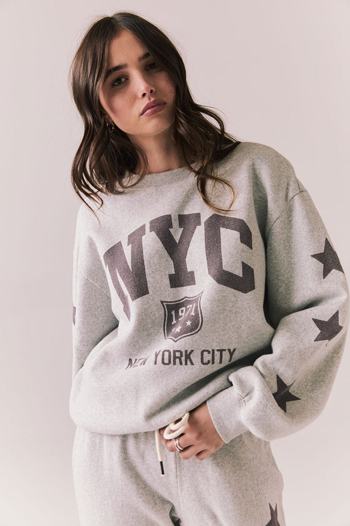 Front view of NYC Stars Pullover in Heather Grey with bold chest lettering and smoky plumb star sleeves against a plain background