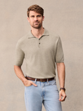 Man in oatmeal knit polo and light wash jeans, hand in pocket, against beige backdrop