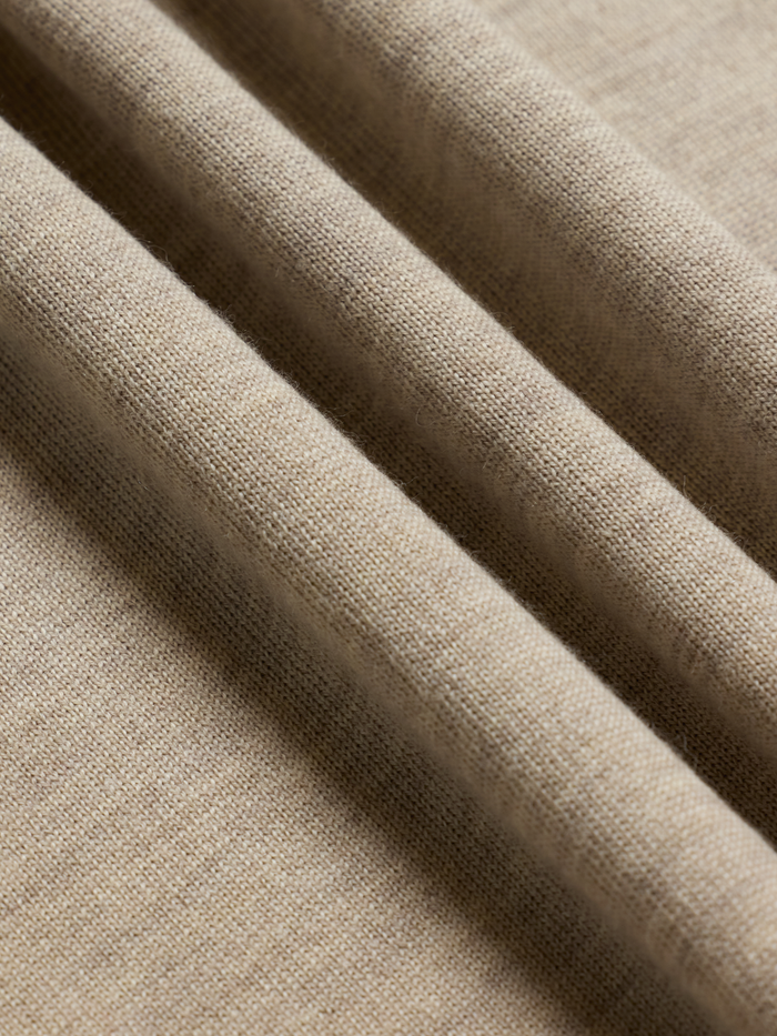 Close-up of oatmeal knit polo fabric texture, ribbed rolled folds