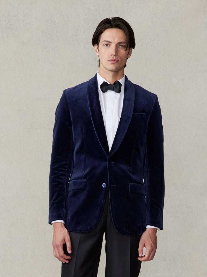 Cropped front view of a ocean blue velvet tuxedo jacket with black tuxedo pants and a white tuxedo shirt.