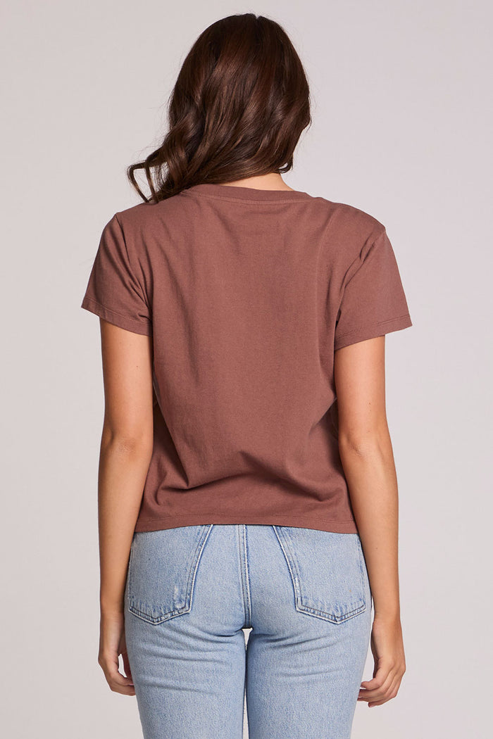 Back view of a woman wearing the Chaser Off Road Race Team Graphic Tee and blue jeans on a neutral background