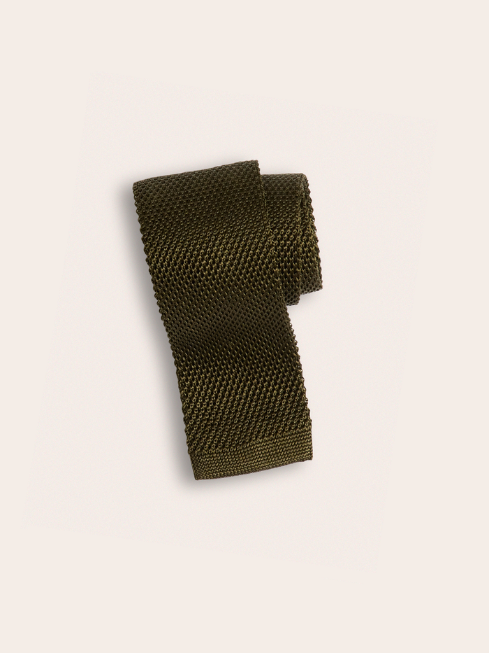 Olive green knit silk tie rolled into a coil on cream background