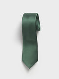Olive green silk necktie rolled into a coil on light grey background