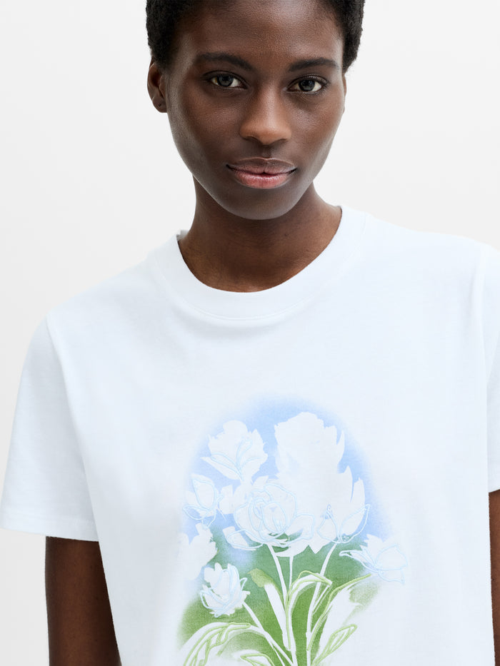 A woman wearing a cotton white T‑shirt with a floral print and embroidered detailing featuring a crew neck and short sleeves in a regular fit.