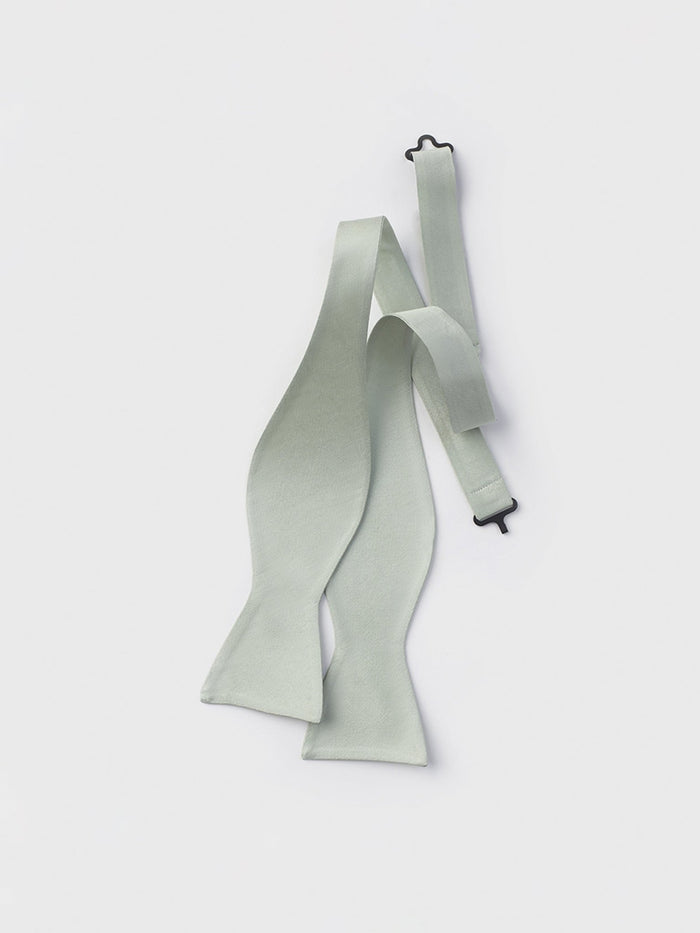 Pale seafoam green silk bow tie untied, laid flat, on white background