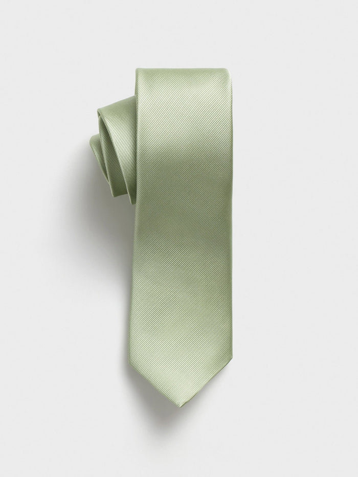Pale seafoam silk necktie rolled at the top on a grey background