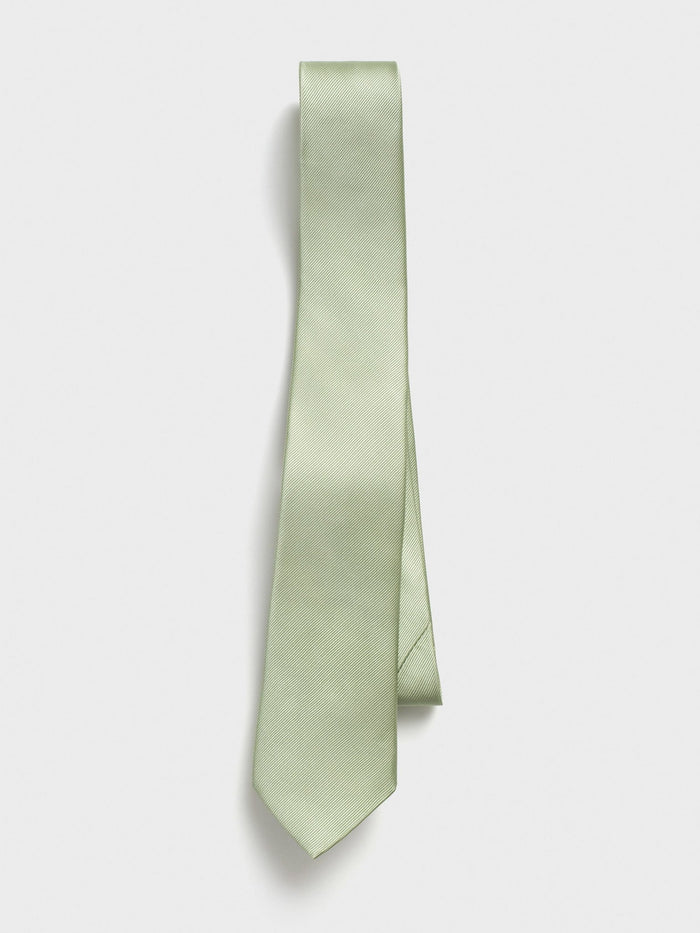 Pale seafoam silk necktie draped with blade crossing on a grey background