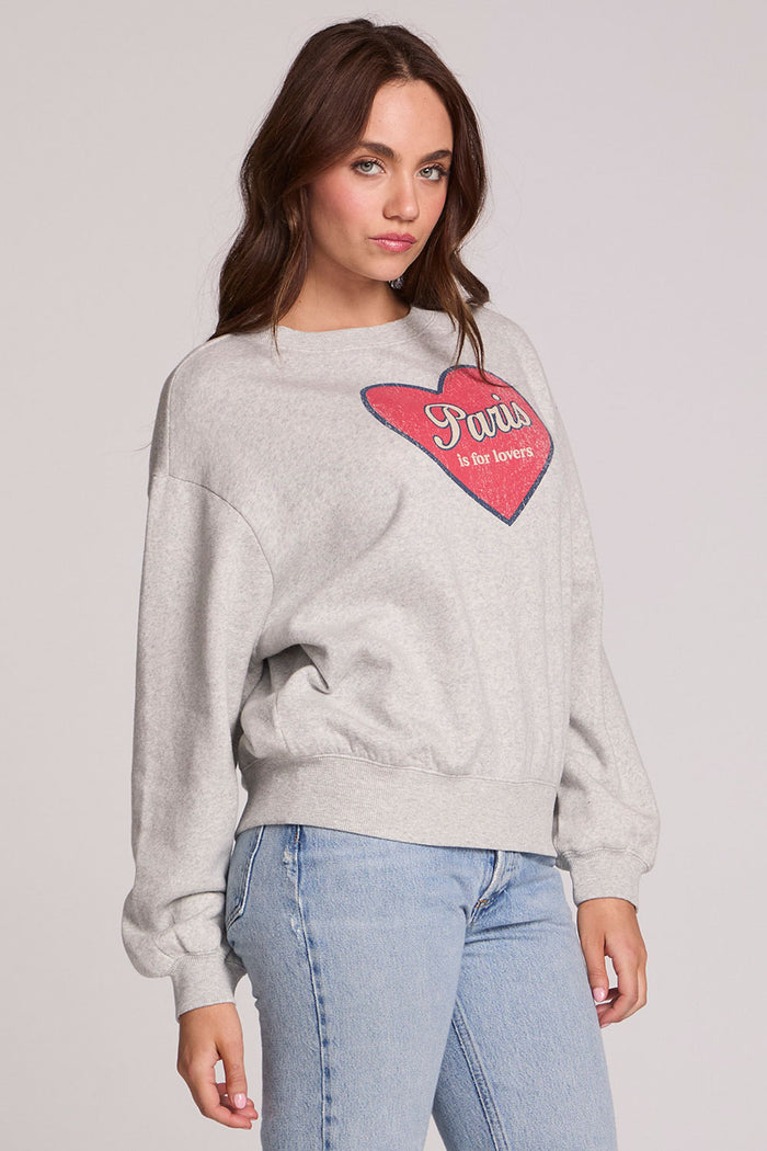 Back view of a woman wearing the Chaser Paris is For Tee on a neutral background with blue jeans