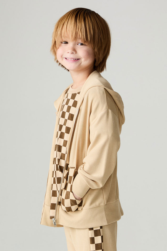 Side view of a boy wearing the Chaser Paxton Zip Up Hoodie Boys Zip Hoodie on a neutral background with hands in pockets