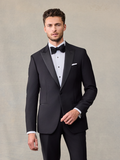 Man in black peak lapel tuxedo with bow tie and pocket square, front view, on beige backdrop