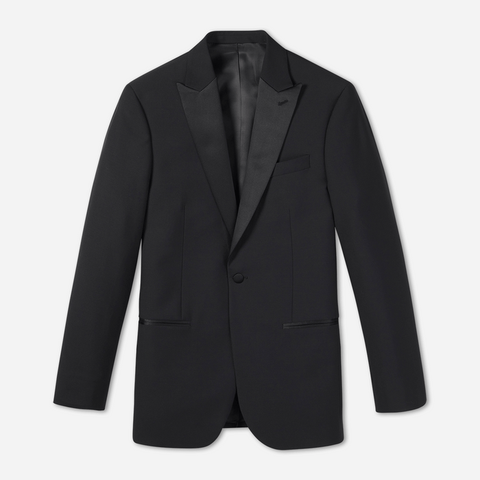 Black peak lapel tuxedo jacket laid flat, satin lapel and covered button, on light grey background
