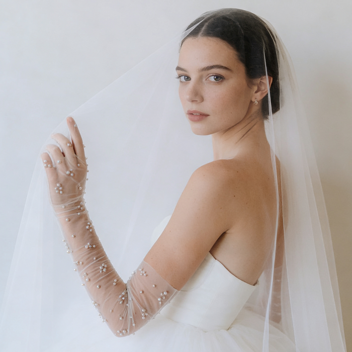 Bride wearing pearl embellished illusion tulle opera gloves with a modern wedding gown during a romantic bridal photoshoot.