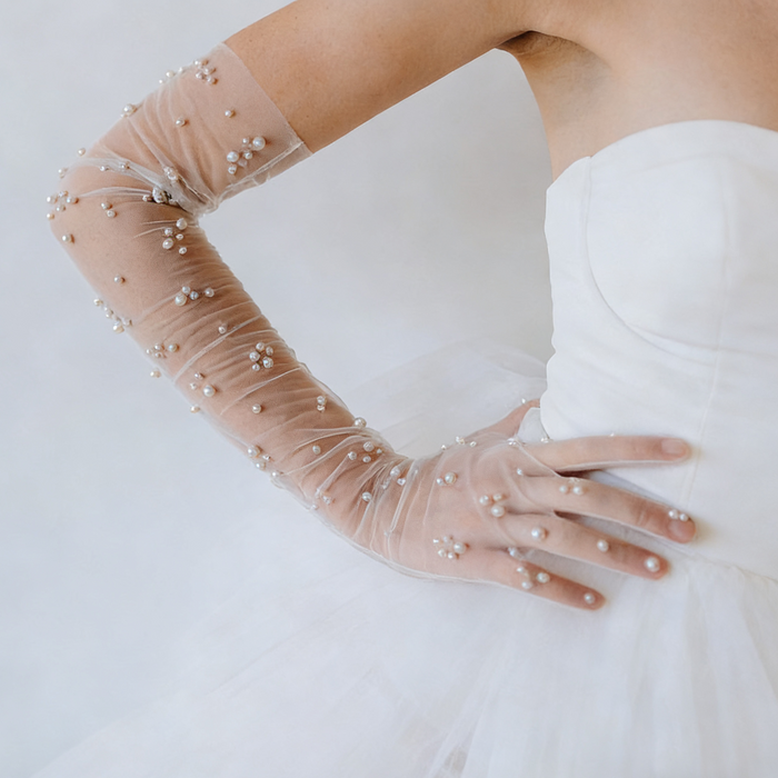 Pearl bridal gloves crafted from sheer illusion tulle with hand sewn faux pearls in delicate scattered clusters.