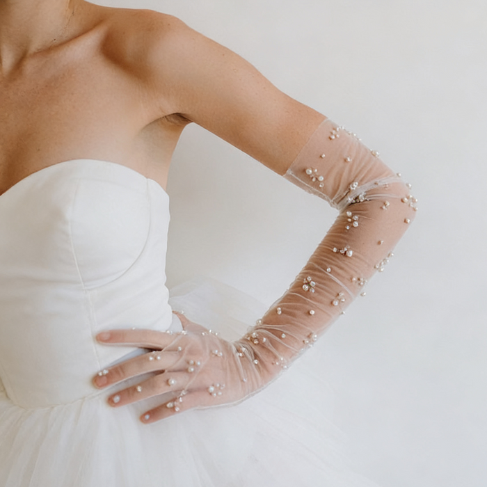 Pearl bridal gloves crafted from sheer illusion tulle with hand sewn faux pearls in delicate scattered clusters.