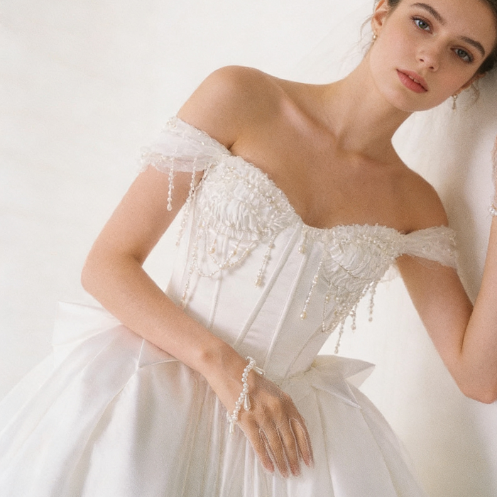Pearl bridal wrist gloves crafted from illusion tulle with hand sewn faux pearls and a wave-shaped cuff.
