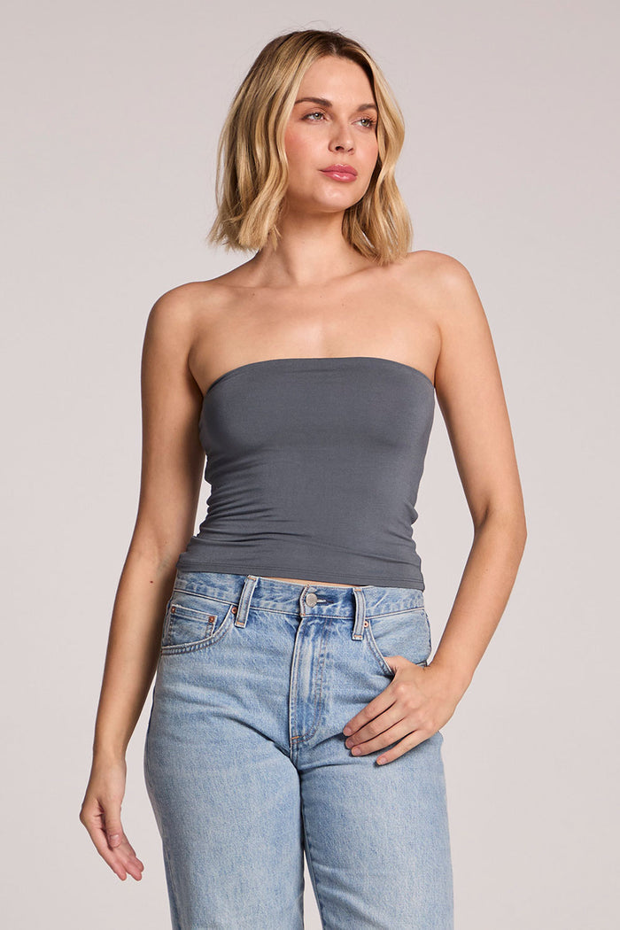 A front view of a woman wearing the Chaser Future Grey Pearl Tube Top on a neutral background with her hand in one pocket