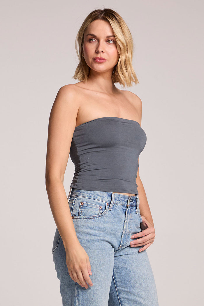 A side angle view of a woman wearing the Chaser Future Grey Pearl Tube Top on a neutral background, looking up